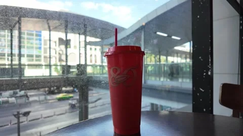 Camera video of red takeaway drink cup placed by window in cafe Stock Footage 325648903