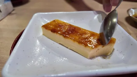 Camera video of spoon cutting into creme brulee on plate Stock Footage 325648943