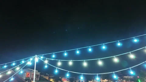 Camera video of string lights glowing at night market Stock Footage 325648889