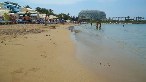 The camera as a view flies along the beach past the tourists. People around r Stock-Footage 77292537