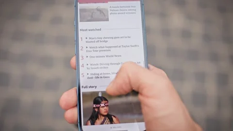 Camera view of man's hand scrolling news on smartphone while walking down street Stock Footage 275979279