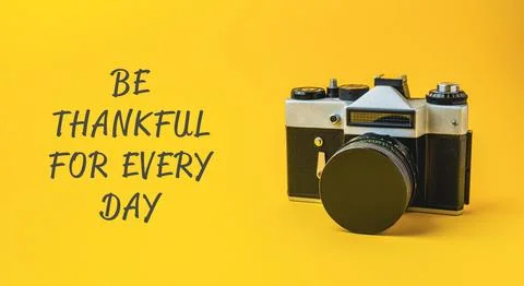 Camera is on a yellow background with the words be thankful for every day Stock Photos