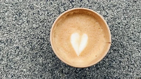 Camera zoom in on a mug of coffee on asphalt saucer. Coffee Latte Art on milk Vídeos de archivo 151742786