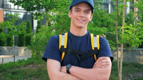 Camera zoom in smiling young man courier food delivery with thermal backpack Stock Footage 157445927