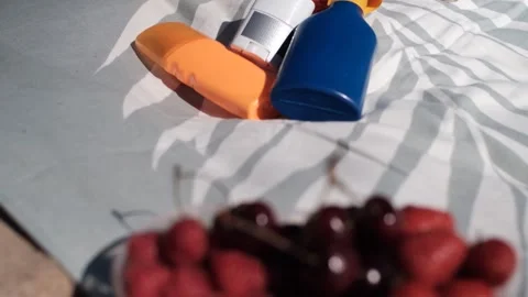 Camera zoom in on a sunscreen set framed by juicy berries in soft focus 스톡 동영상 313290628