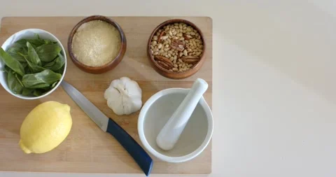 Camera is zooming to center cutting board with basil, cheese, garlic on counter, Stock Footage 341393754