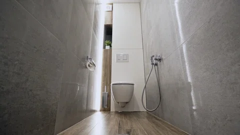 Camera zooming out from ceramic flush toilet inside narrow restroom with tiled Stock-Footage 110734598