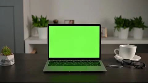 Camera zooms in on the desktop at home with an open laptop with green chroma key Stock Footage 198513897