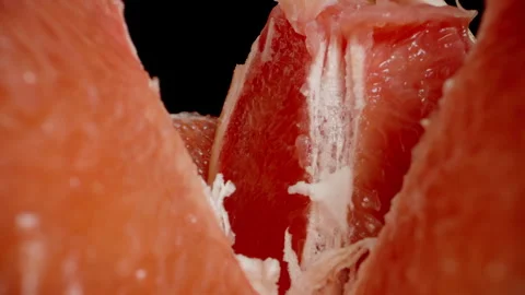 The camera zooms into the inside of a broken apart grapefruit, capturing a macro Stock Footage 263133380