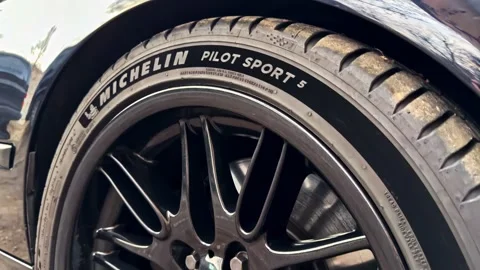 The camera zooms in on a premium Michelin Pilot Sport 5 summer tire mounted on Stock Footage 335442351