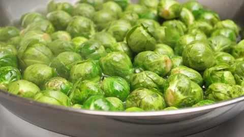Camera zooms in on roasting brussel sprouts many sprouts in a shiny pan. Roasted Stock Footage 301920214