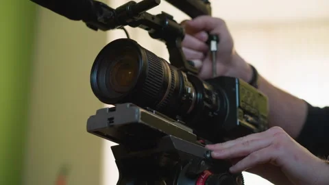 Cameraman adjusting camera setup on tripod, focusing equipment for film Stockbeeldmateriaal 317545510