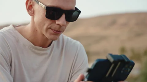 A cameraman in sunglasses moves a drone controller and watch it fly. medium shot Stock Footage 252669815