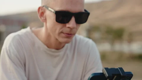 A cameraman in sunglasses moves a drone controller and watch it fly. medium shot Stock Footage 252672728