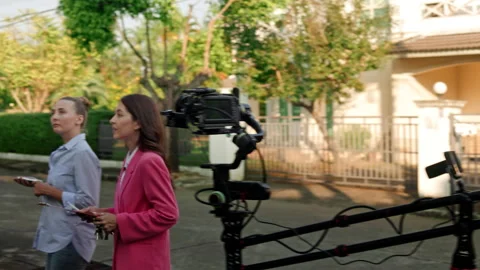 A cameraman is using a crane-mounted camera to film two women outside, with a Stock Footage 240120037