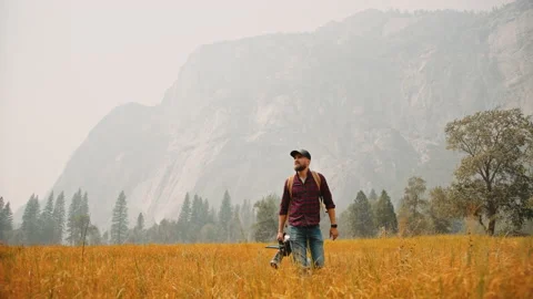 Cameraman walking at valley with his camera and looking on mountains 2 Stock Footage 138321784