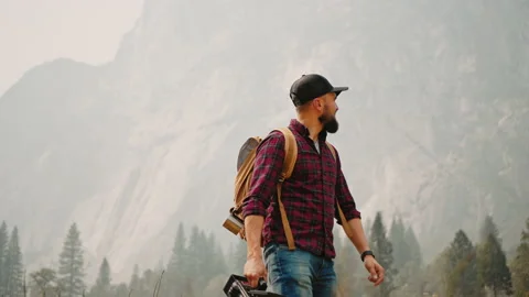 Cameraman walking at valley with his camera and looking on mountains Video stock 138322261