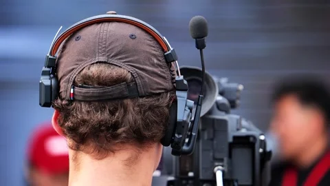 Cameraman wearing a headset with a microphone operating a video camera during an Stock Footage 318846985