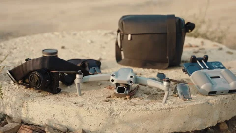 A cameraman's gear: drone, controller, bag, camera - wide shot,sunset Stock Footage 252672852