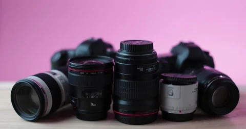 Cameras and camera lenses lying on modern table with simple pink background Stock Footage 237546345