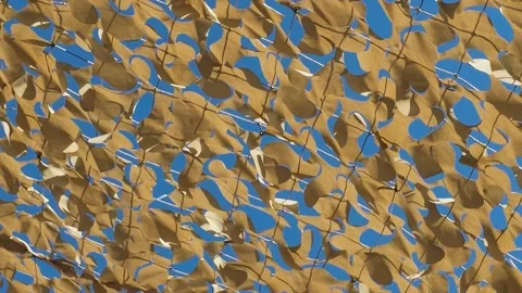 Camouflage netting creating a dappled light effect against a clear blue sky Stock Footage 337325961