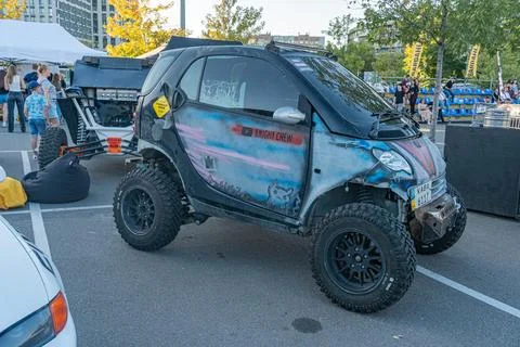 A camouflage-patterned, oversized-tire golf cart blue, green on a paved sur.. 스톡 사진