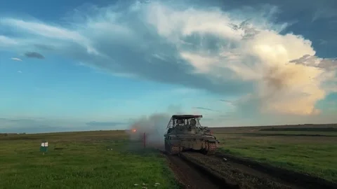 Camouflaged tank firing and exploding on a rural test field Stock Footage 313255450