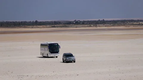Camp car and bus walking on the sand under the hot sky in the desert - Stock Footage 240993629