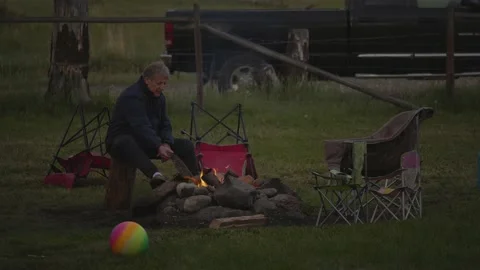 Camp fire. A man is sitting by the fire. evening. Видео 156769624