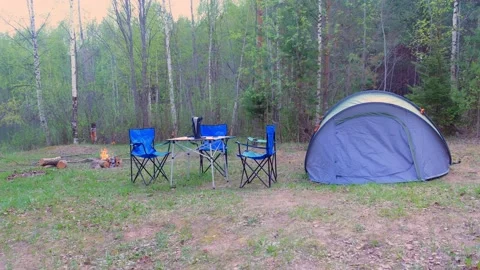 Camp tent, chairs, table and campfire in forest camping, nature trip at Summer. Stock Footage 136021280