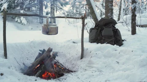 Camp in the winter forest. A kettle over the fire. Stockbeeldmateriaal 148150461
