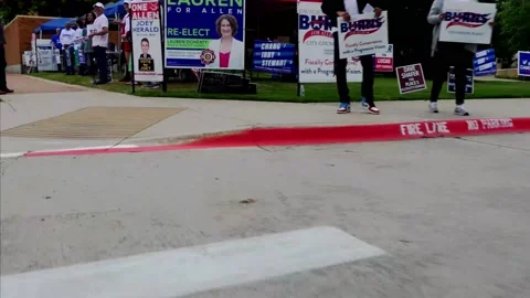 Campaign workers crowd near polling place entrance to greet arriving voters Vídeo Stock 153342876