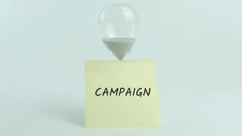 Campaign written on yellow sticky note placed on hourglass on white Stock Footage 313465963
