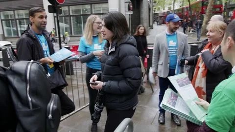 Campaigners hand leaflets to voters outside the polling place in London Vídeos de archivo 345298836