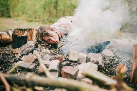 Camper blowing into campfire to get fire started. Stock Photos