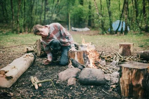 Camper blowing into campfire to get fire started. Stock Photos