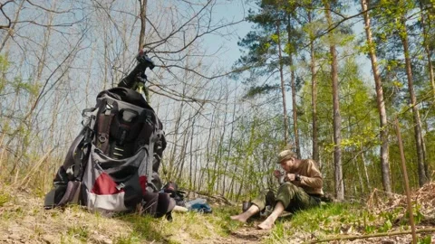 Camper Enjoying Tea in a Forest with Backpack and Spring Sunlight Vídeo Stock 316297474