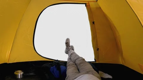Camper lying inside open tent, view of legs against outside background, alpha Stock Footage 159797606