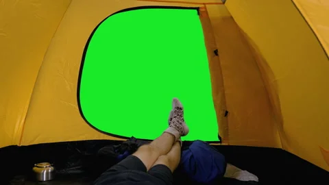 Camper lying in open tent, view of his legs in woolen socks against green screen Video stock 159797736
