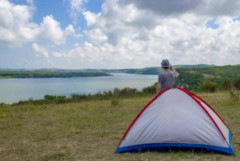 A camper is making a phone call while standing near tent Stockfoto's