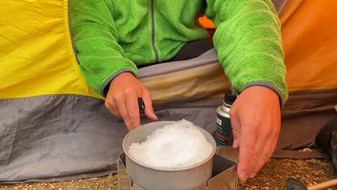 Camper melting snow close-up view at a tent entrance in Svaneti, Georgia Stock Footage 343769940