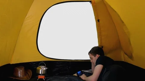 Camper relaxing inside open tent watching something in smartphone, alpha channel Video stock 159792043