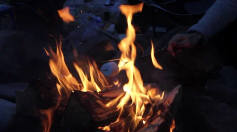 A camper roasts a marshmallow over a camp fire Stock Footage 37623667
