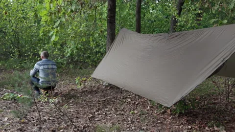 Camper Sitting on Stool and Eating Dinner Near Tarp at Dusk 스톡 동영상 346550855