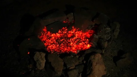 Camper stoking a glowing campfire with a log. Stock Footage 88368907