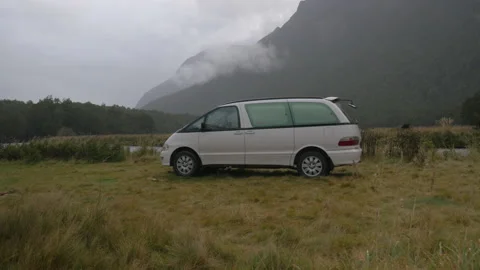 A campervan set in a meadow surrounded by mountains, in New Zealand Stock Footage 219201187