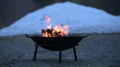 Campfire burning in firebowl, early springtime, snow in the background. Stock Footage 154051863