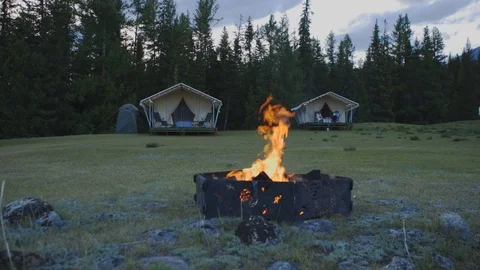 Campfire is burning in the forest against the backdrop of snow-capped mountains Stock Footage 124495980