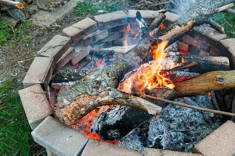 Campfire with burning logs and glowing flames outdoors Stock Photos