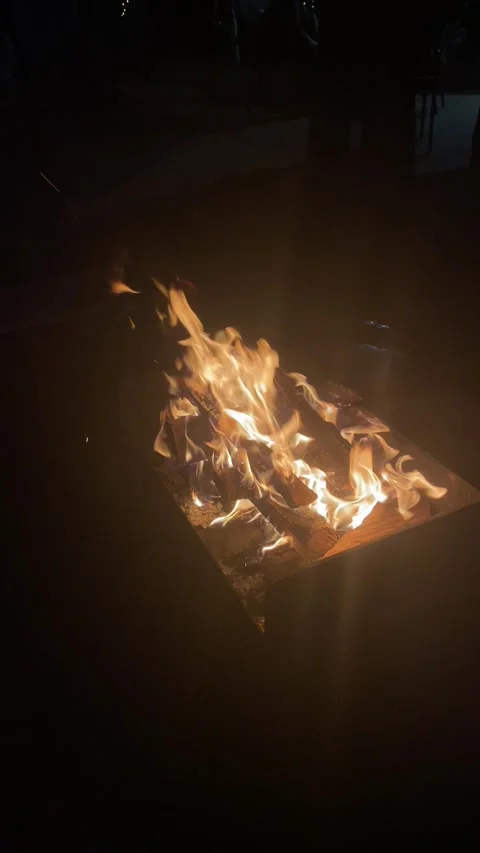 Campfire burns brightly inside a metal fire pit at night Stock Footage 343567417